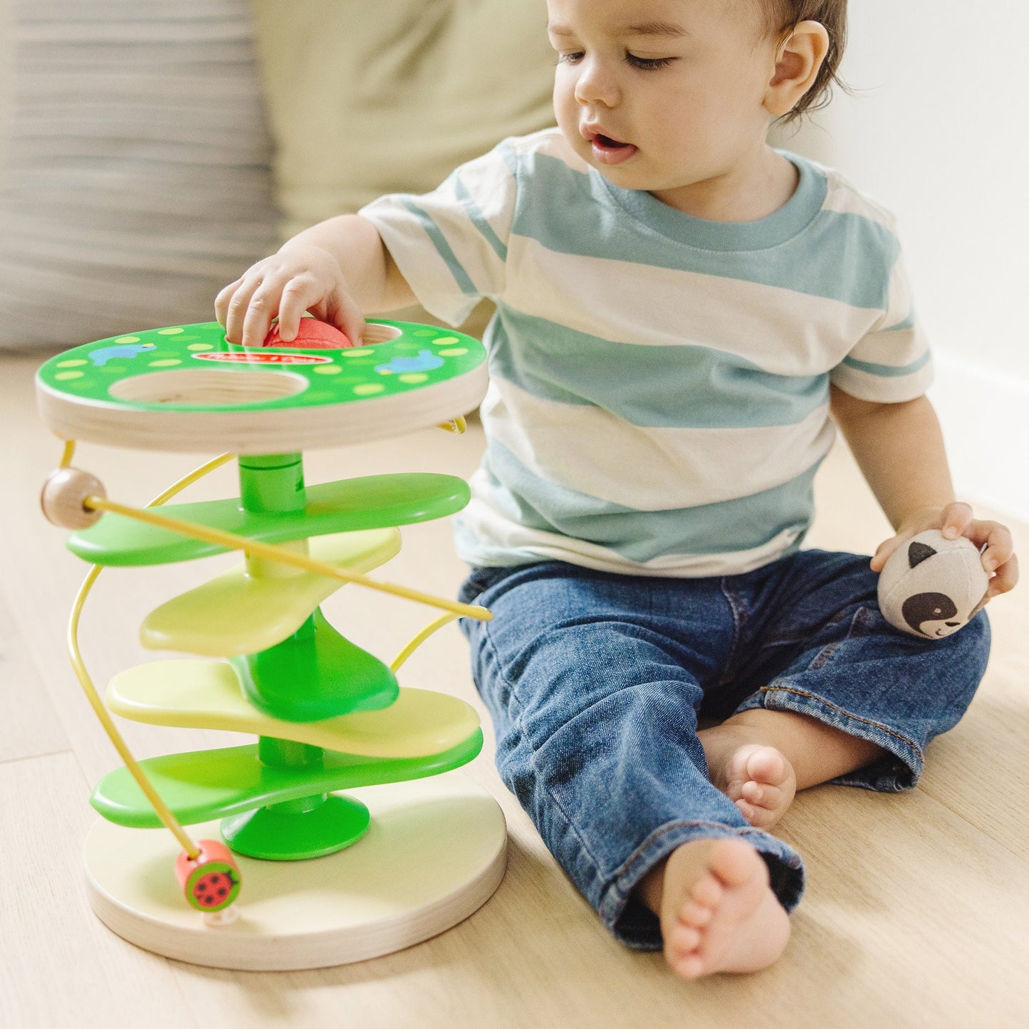 A kid playing with The Melissa & Doug Rollables Treehouse Twirl Infant and Toddler Toy (3 Pieces)
